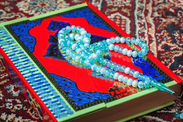 Colorful Koran with rosary on the wooden background. Holy book for Muslims for Ramadan concept