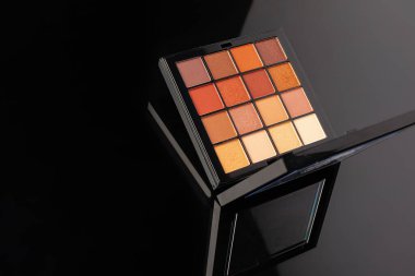 Profesyonel göz farı paleti. Siyah masanın üzerinde parçalanmış göz gölgeleri var..