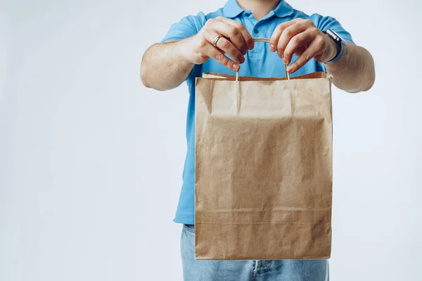 Homem irreconhecível no pólo azul com ordens de entrega de alimentos contra fundo cinza — Fotografia de Stock