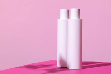 Parlak pembe arka planda cilt ürünleri kapları