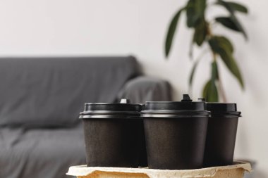 Koyu kahve fincanlarını kabın içinde götürür.