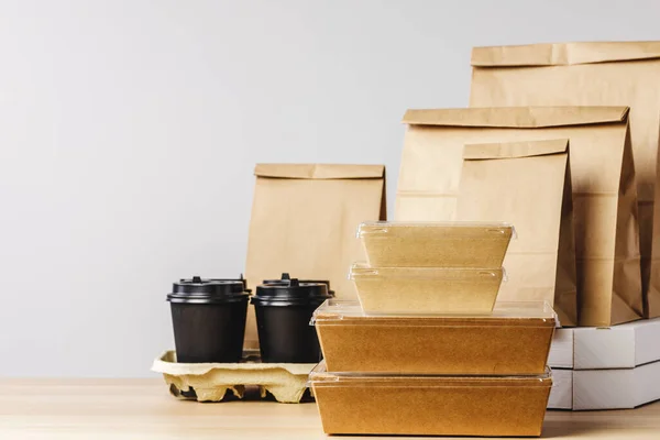 Muchos envases de comida para llevar diversos, caja de pizza, tazas de café y bolsas de papel sobre fondo gris claro —  Fotos de Stock