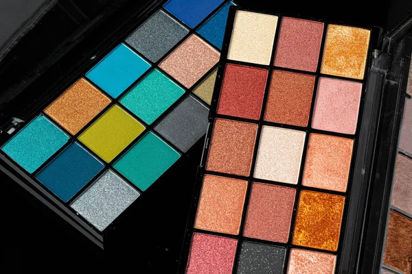 Professional pallet of eyeshadow. Multicoloured crumbled eye shadows on black table. — Stock Photo, Image