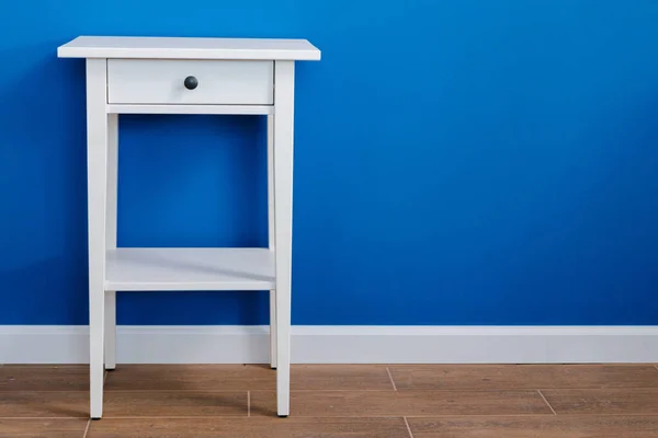 White wooden nightstand table against blue wall — Stock Photo, Image