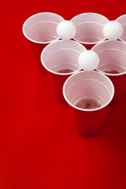 Bardaklar ve plastik top kırmızı arka planda. Bira pong oyunu
