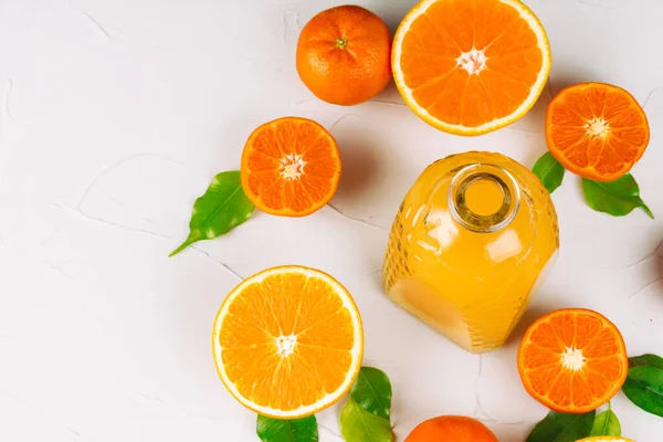 Glass bottle of orange juice with halves of ripe oranges — Stock Photo, Image