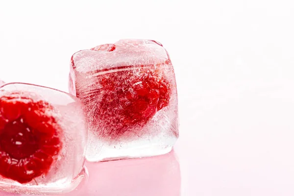 Малинові кубики льоду на рожевому глянсовому фоні — стокове фото