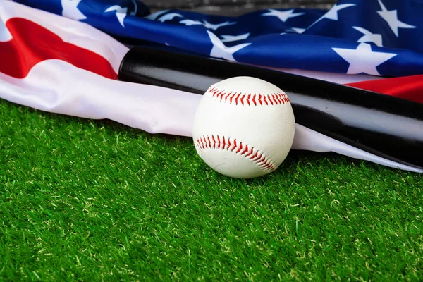 Baseballschläger und Ball mit amerikanischer Flagge auf Gras — Stockfoto