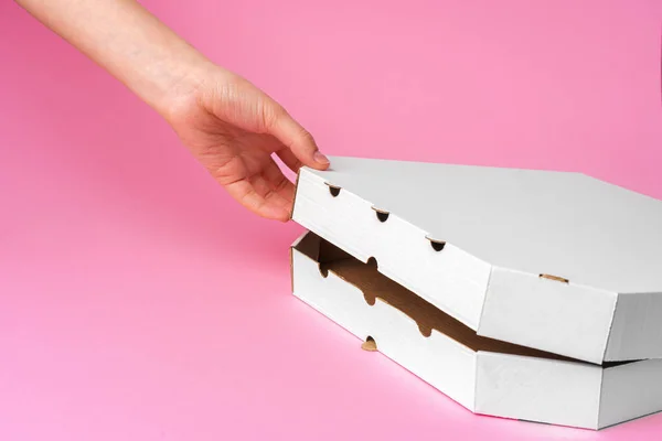 Женщина открывает коробку для доставки пиццы на розовом фоне — стоковое фото