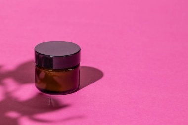 Parlak pembe arka planda cilt ürünleri kapları