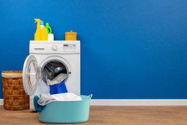 Çamaşır makinesi ve mavi duvar arkaplanı.