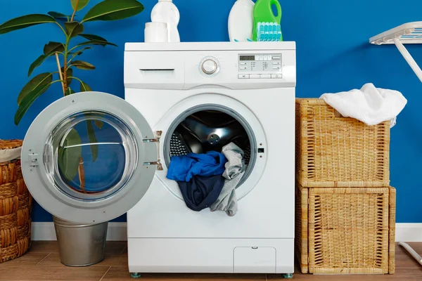 Washing machine with laundry on blue wall background — Stock Photo, Image