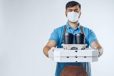 Koruyucu maskeli bir teslimatçı ve elinde yemek tutan tıbbi eldivenler var. Covid-19 salgını sırasında hijyen kurallarına uymak