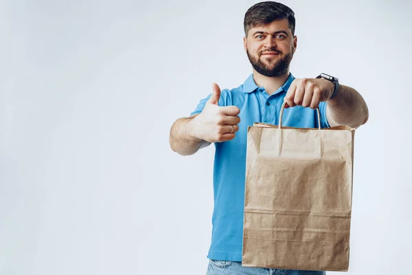 Entrega hombre con la orden de la bolsa de comestibles sobre fondo gris — Foto de Stock