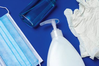 Coronavirus önleme. Mavi arka planda yüz maskesi, eldiven, sabun ve dezenfektan.