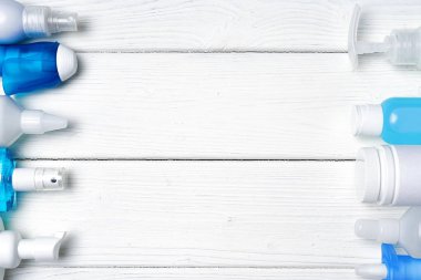 Ahşap zemin üzerinde el dezenfektanları, sıvı sabun ve tıbbi hazırlıklar olan bir sıra şişe.