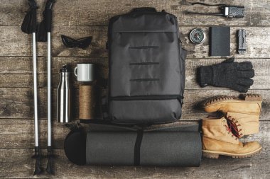 Sırt çantası ve yürüyüş ekipmanları ahşap arka planda, üst manzara
