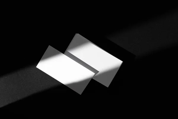 Tarjetas de visita en blanco sobre fondo negro. Foto creativa con sombras —  Fotos de Stock