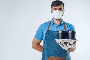 Tıbbi eldivenli bir adam kahve fincanı veriyor. Covid-19 koronavirüs salgını sırasında güvenli servis