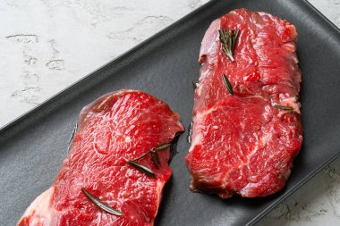 Siyah seramik tabakta iki taze çiğ biftek.