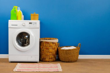 Çamaşır makinesi ve mavi duvar arkaplanı.