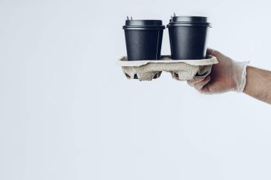 Tıbbi eldivenli bir adam kahve fincanı veriyor. Covid-19 koronavirüs salgını sırasında güvenli servis