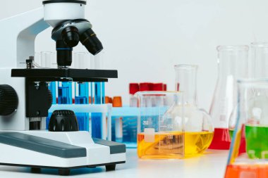 Laboratuvardaki masada mikroskop ve test tüpleri, kapatın.