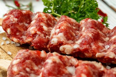 Çiğ lula kebabı şişte ve ahşap tahtada baharatlar.