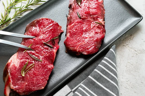 Dos filetes frescos de carne cruda en plato de cerámica negra — Foto de Stock