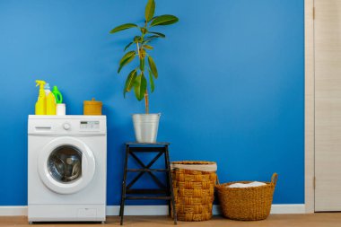 Çamaşır makinesi ve mavi duvar arkaplanı.