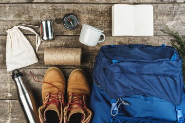 Sırt çantası ve yürüyüş ekipmanları ahşap arka planda, üst manzara