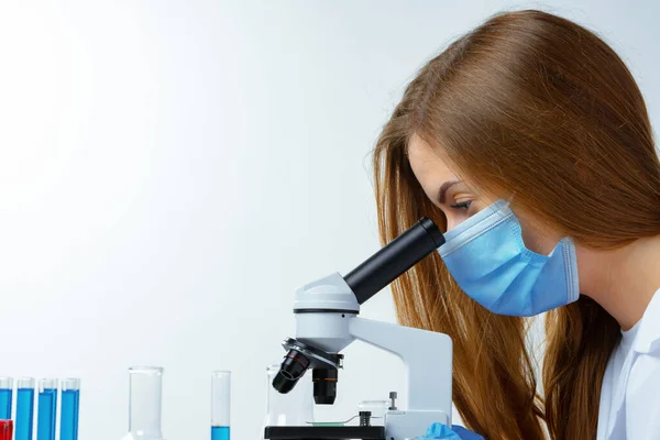 Femme scientifique regardant à travers un microscope en laboratoire — Photo