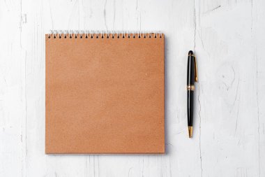 Tahta masadaki kalemle kahverengi açık not defterinin üst görünümü