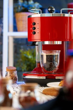 Mutfak tezgahında bardak olan kırmızı kahve makinesi.