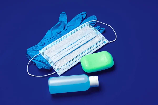 Prevenção de coronavírus. Máscara facial, luvas, sabão e desinfetante sobre fundo azul — Fotografia de Stock