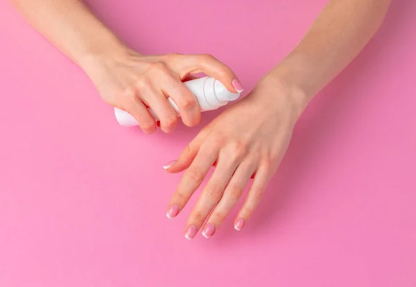 Vrouwelijke hand houden huidverzorgingsproduct fles op roze — Stockfoto