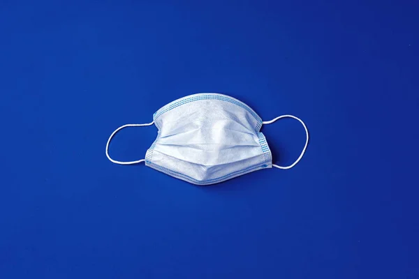 Medical face mask on blue background. Coronavirus prevention concept