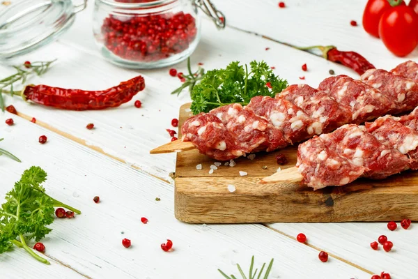 Raw lula kebab on skewers with spices on wooden board — Stock Photo, Image