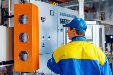 Kablo fabrikasının makine kontrol panelindeki fabrikada çalışan adam.