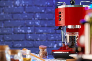 Mutfak tezgahında bardak olan kırmızı kahve makinesi.