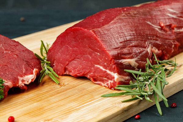 Slice of raw beef fillet on wooden board