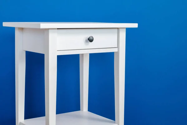 White wooden nightstand table against blue wall — Stock Photo, Image