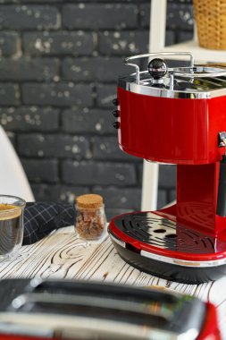 Mutfak tezgahında bardak olan kırmızı kahve makinesi.