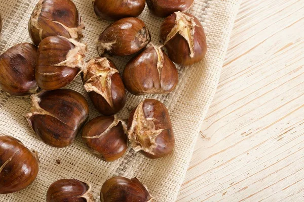 Geroosterde kastanjes op houten ondergrond — Stockfoto