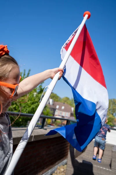 Une personne portant des lunettes de soleil agitant le drapeau national néerlandais — Photo