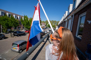 Hollanda bayrağını sallayan güneş gözlüğü takan biri.