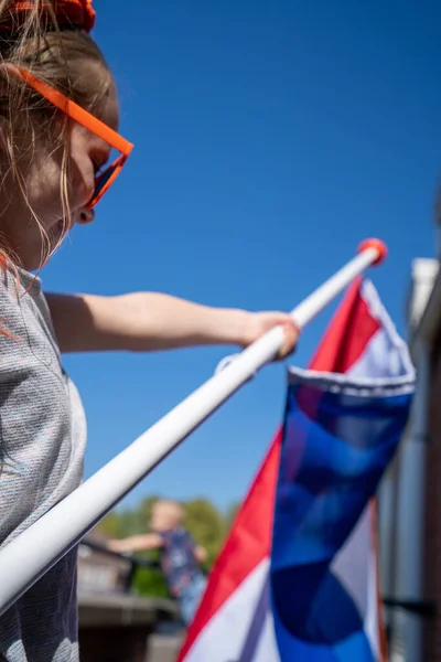 Una persona con gli occhiali da sole sventola la bandiera nazionale olandese — Foto Stock