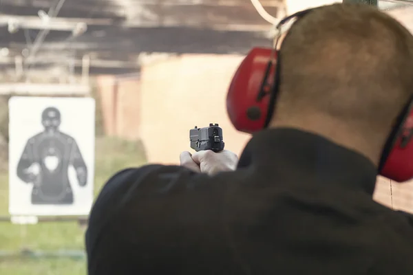 A disparar com uma pistola. Homem apontando pistola na faixa de tiro . — Fotografia de Stock