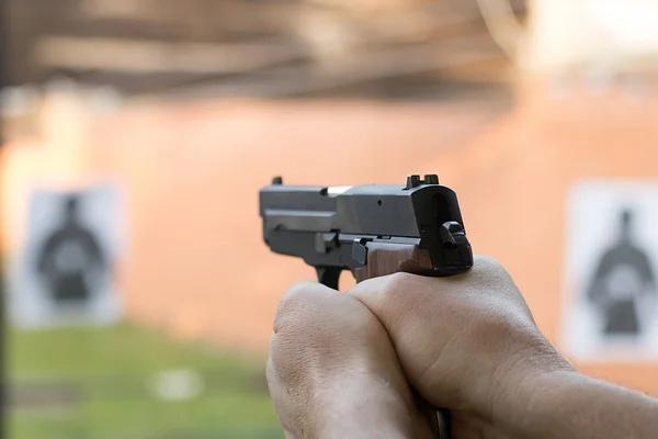 A disparar com uma pistola. Homem apontando pistola na faixa de tiro . — Fotografia de Stock