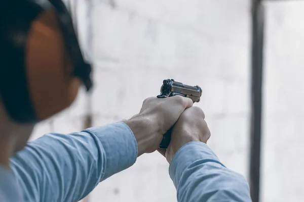 Disparar con una pistola. Hombre apuntando pistola en el campo de tiro . — Foto de Stock